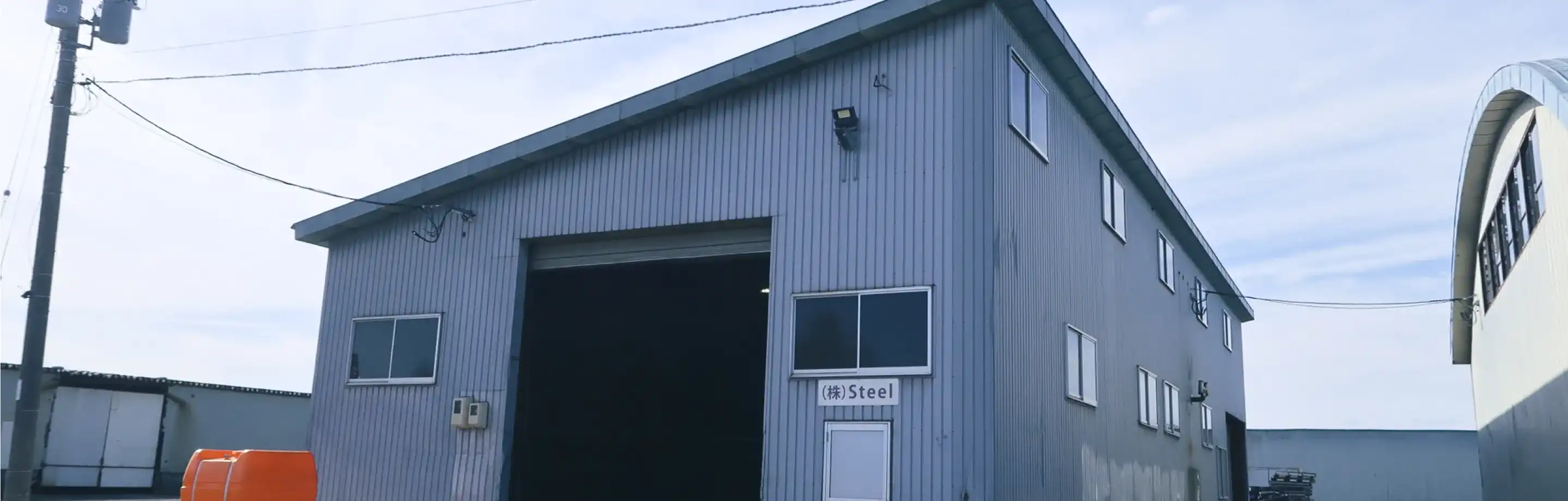 広大な敷地に建つ株式会社Steelの鉄骨造工場建屋と青空