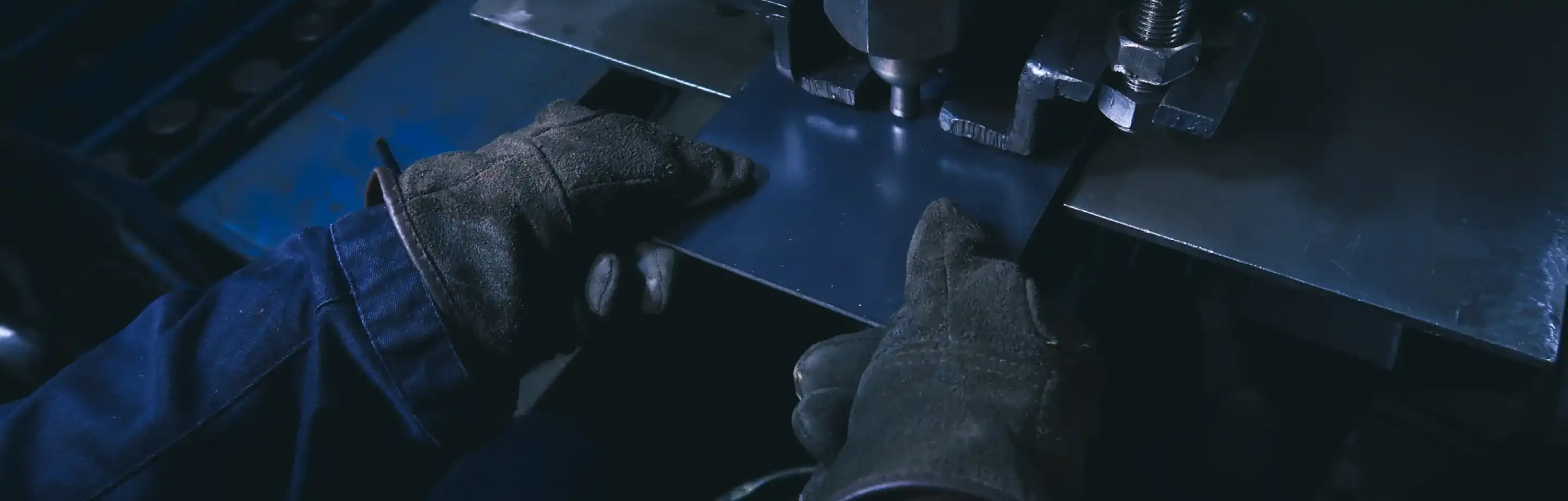 専用の工作機械を用いて鉄板に精密な穴あけ・プレス加工を施す様子